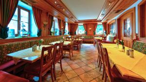 een restaurant met houten tafels, stoelen en ramen bij Gasthof zur Post in Raisting
