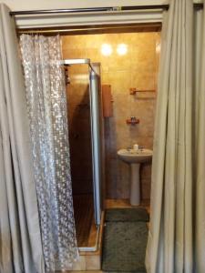 een badkamer met een douchegordijn en een wastafel bij Old Post Office Inn in Graskop