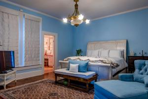 Schlafzimmer mit blauen Wänden, einem Bett und einem Stuhl in der Unterkunft Tolley House in Lynchburg