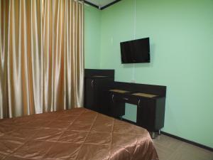 a bedroom with a bed and a desk and a television at Hotel Persona in Yuzhnoural'sk