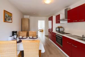 a kitchen with red cabinets and a table with chairs at Gästehaus Höltig in Havekost