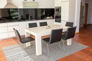 a kitchen with a white table and black chairs at Regada House in Vieira do Minho