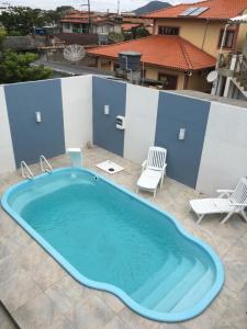 uma grande piscina num pátio com duas cadeiras em Casa com Piscina temporada em Florianópolis
