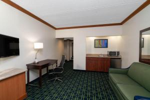 ein Hotelzimmer mit einem Sofa und einem Schreibtisch in der Unterkunft Wingate by Wyndham Fletcher at Asheville Airport in Fletcher