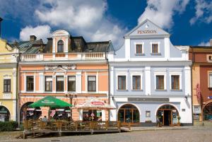 a building with tables and umbrellas in front of it at Penzion U Zvonu in Rychnov nad Kněžnou