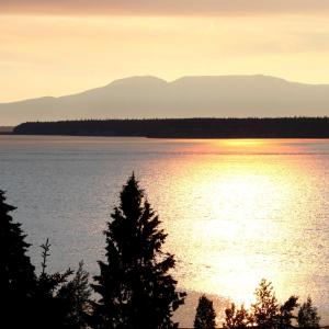 um pôr-do-sol sobre um lago com árvores e montanhas em Susitna Place B&B em Anchorage