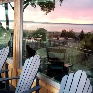 2 Stühle auf einem Balkon mit Blick auf das Wasser in der Unterkunft Susitna Place B&B in Anchorage