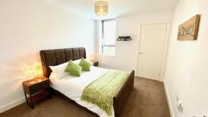 a bedroom with a bed with white sheets and green pillows at Friars House, Stafford by BELL Apartments in Stafford