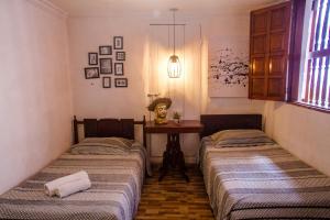 two beds in a room with a table and a window at Casa San Benito Abad in Cartagena de Indias