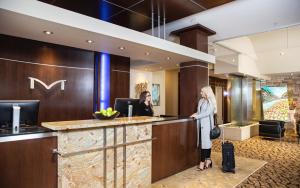 dos mujeres de pie en una recepción en el vestíbulo de un hotel en Metterra Hotel on Whyte en Edmonton