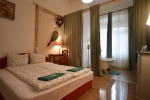 a bedroom with a bed and a bathroom with a tub at Tulipán Villa Panzió in Szolnok