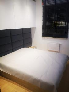 een slaapkamer met een wit bed en een raam bij Apartament Przy Galerii in Radom