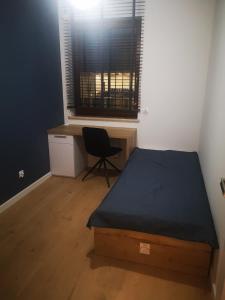 een slaapkamer met een bed, een bureau en een raam bij Apartament Przy Galerii in Radom