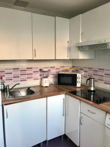 a kitchen with white cabinets and a sink and a microwave at Centro Madrid Rio - Monederos C in Madrid