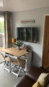 a living room with a table and a tv at Appley Lodge Glan Gwna in Caernarfon