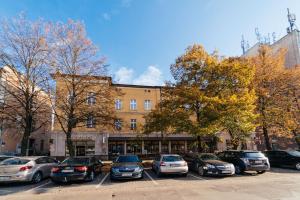 un grupo de autos estacionados en un estacionamiento frente a un edificio en Apartament Copernicus Olsztyn, en Olsztyn