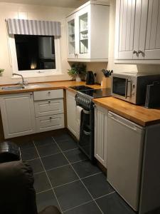 a kitchen with white cabinets and a stove top oven at Appley Lodge Glan Gwna in Caernarfon