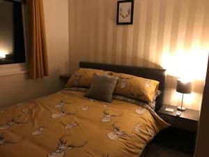 a bedroom with a bed with a blanket with deer on it at Appley Lodge Glan Gwna in Caernarfon