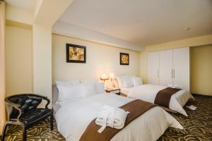 ein Hotelzimmer mit zwei Betten und einem Stuhl in der Unterkunft Hotel Nobility in Lima