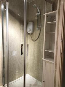 a shower with a glass door in a bathroom at Appley Lodge Glan Gwna in Caernarfon