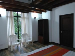 ワッタラにあるEldorado Apartments 3BR Apart F2P3の白い椅子2脚とベッド1台と窓のある寝室