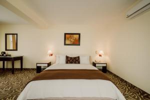 1 dormitorio con 1 cama grande y 2 mesas en Hotel Nobility, en Lima