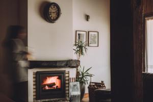 a fireplace in a living room with a clock on the wall at Villas do Agrinho in Valdosende