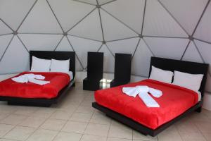 2 camas con colchas rojas en una habitación con tienda de campaña en Hotel & Glamping Huasca Sierra Verde, en Huasca de Ocampo