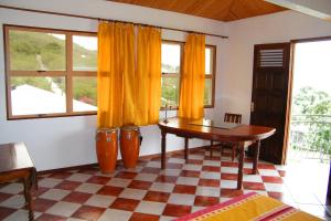 sala de estar con mesa y cortinas amarillas en Villa de charme avec piscine MQAA07, en Les Anses-dʼArlet