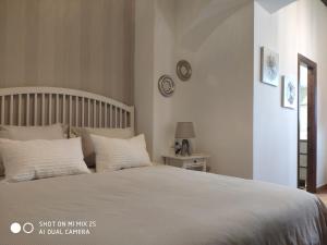 1 dormitorio con 1 cama grande con sábanas y almohadas blancas en Casa en la Juderia en Carmona