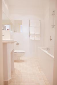 a white bathroom with a tub and a toilet and a sink at Rudolfo Hotel in Lviv