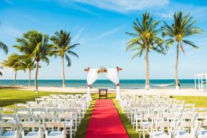a wedding ceremony on the beach with palm trees at The Grand Caymanian Resort in George Town