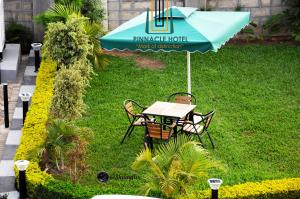 Pinnacle Hotel Mbarara في Mbarara: طاولة وكراسي تحت مظلة في العشب