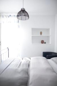 a white bedroom with a bed and a chair at Little house - Hiška in Izola