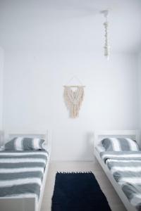 2 camas en una habitación blanca con alfombra azul en Little house - Hiška, en Izola