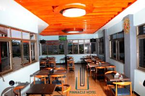 a restaurant with wooden tables and chairs and windows at Pinnacle Hotel Mbarara in Mbarara