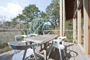 a wooden table and chairs on the deck of a cabin at Hepburn Spa Pavilions in Hepburn Springs