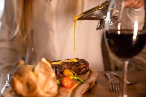 a person pouring wine into a sandwich and a glass of wine at H&oacute;tel Valaskj&aacute;lf in Egilsstadir