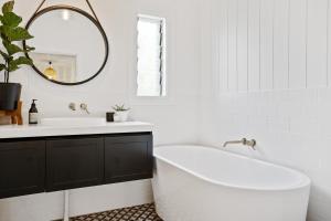 uma casa de banho com uma banheira, um lavatório e um espelho. em Hideaway on Keats - Keats Street, Byron Bay em Byron Bay