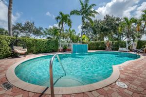 a swimming pool in a yard with palm trees at Best Western Plus Palm Beach Gardens Hotel & Suites and Conference Ct in Palm Beach Gardens