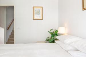 a white bedroom with a bed and a lamp at Beachfront Manly Apartment With Balcony & Parking DUPLICATE in Sydney