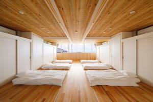 a row of beds in a room with a wooden ceiling at 渚泊魚津丸 in Motoshin