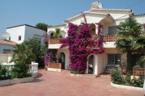 un bâtiment avec des fleurs violettes sur son côté dans l'établissement Villa Sol, à Empuriabrava