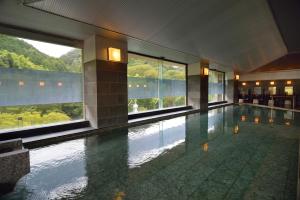 a large swimming pool in a building with windows at Shuzenji Onsen Katsuragawa in Izu