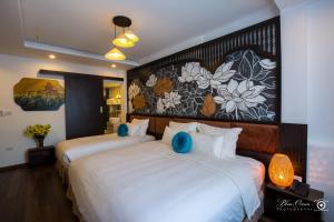 een hotelkamer met 2 bedden en een schilderij aan de muur bij Hanoi Center Silk Lullaby Hotel and Travel in Hanoi