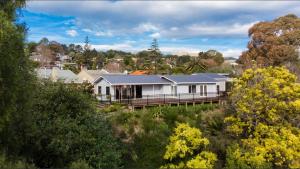 a large white house with a porch in a forest at The House at No 1 in Havelock North