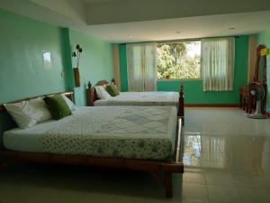 two beds in a room with green walls at Green Home in Khao Lak