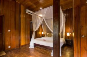 a bedroom with a white bed with a canopy at Wat Bo House in Siem Reap