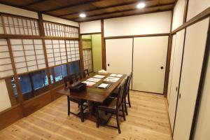 Zimmer mit einem Tisch mit Stühlen und Fenstern in der Unterkunft Ichimatsu-an in Kyoto