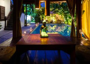 a figurine sitting on a table in front of a pool at Wat Bo House by Angkor Stays in Siem Reap